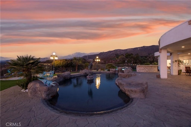 pool at dusk with a mountain view and a patio area