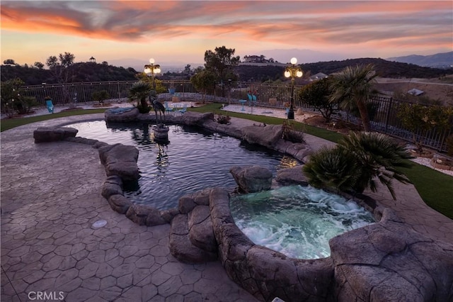 exterior space featuring a pool with hot tub, a garden pond, and a patio