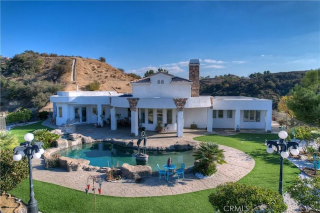 rear view of property with a yard, a mountain view, and a patio