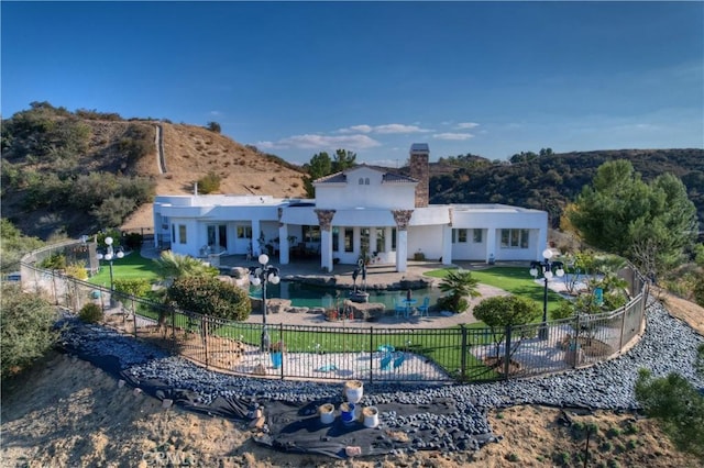 back of house featuring a fenced in pool and a patio