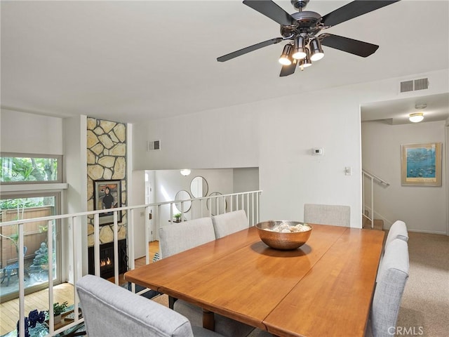 dining area with a stone fireplace and carpet floors