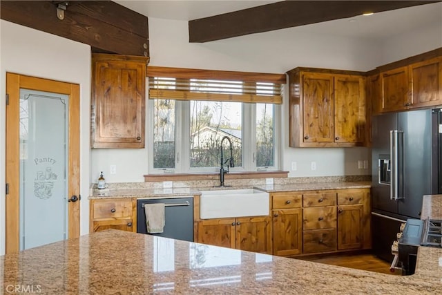 kitchen featuring beam ceiling, appliances with stainless steel finishes, sink, and light stone counters