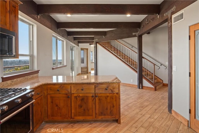 kitchen with black microwave, stainless steel stove, light hardwood / wood-style floors, and kitchen peninsula