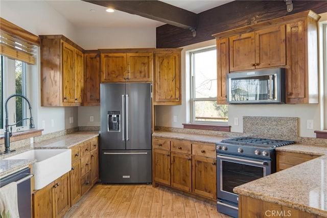 kitchen featuring sink, light stone counters, light hardwood / wood-style flooring, high quality appliances, and plenty of natural light