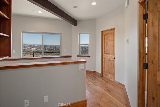 corridor featuring beam ceiling and light hardwood / wood-style floors