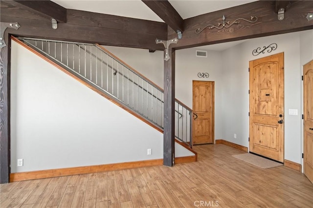 foyer entrance featuring beam ceiling and light hardwood / wood-style floors