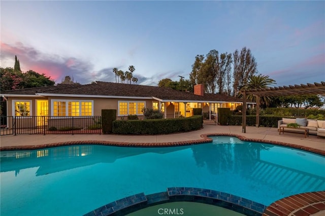 pool at dusk featuring a pergola and a patio area