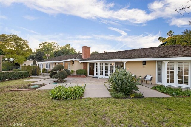 back of property with a patio, a yard, and french doors