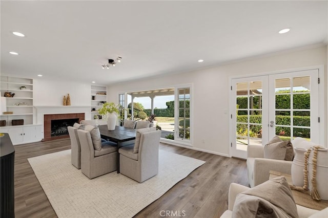 dining space featuring wood-type flooring, plenty of natural light, a fireplace, and french doors