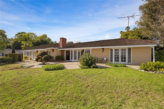 rear view of property featuring a patio, a yard, and french doors