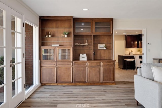 bar with ornamental molding and light hardwood / wood-style floors