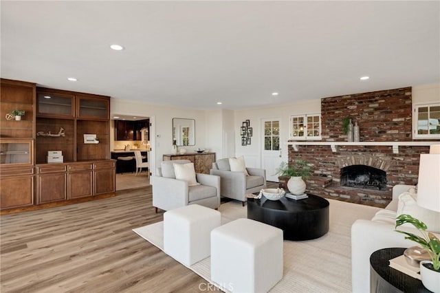 living room featuring a brick fireplace and light hardwood / wood-style flooring