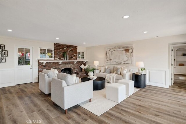 living room featuring wood-type flooring and a brick fireplace