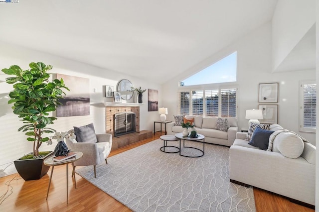 living room with a brick fireplace, a healthy amount of sunlight, and hardwood / wood-style floors