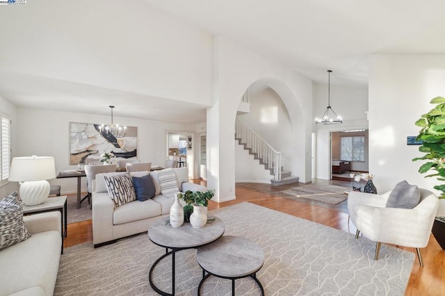 living room featuring wood-type flooring, high vaulted ceiling, and an inviting chandelier