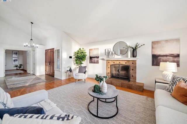 living room with an inviting chandelier, high vaulted ceiling, a fireplace, and hardwood / wood-style floors