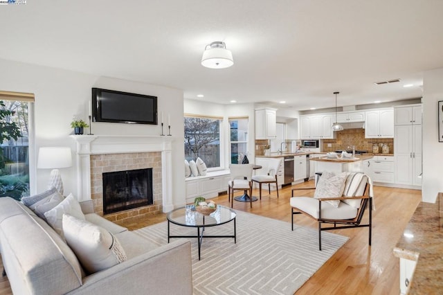 living room with a fireplace, light hardwood / wood-style flooring, and a wealth of natural light