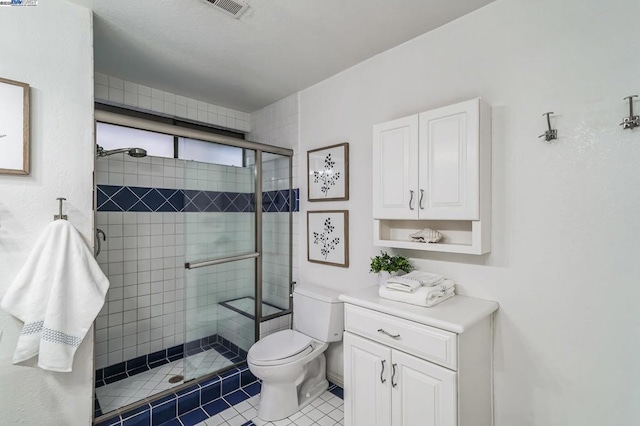 bathroom featuring tile patterned flooring, toilet, and a shower with shower door