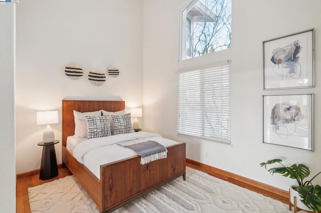 bedroom featuring a towering ceiling and light wood-type flooring