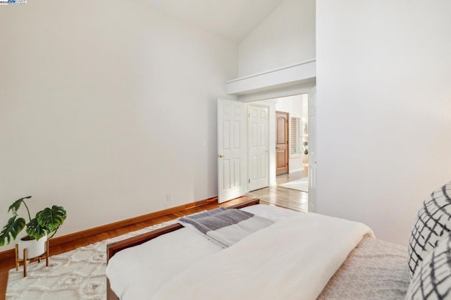 bedroom featuring high vaulted ceiling and light hardwood / wood-style floors