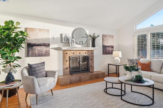 living room featuring hardwood / wood-style flooring, a tiled fireplace, and lofted ceiling