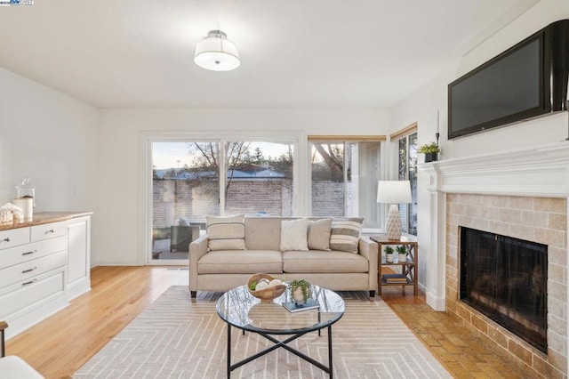 living room with a tiled fireplace and light hardwood / wood-style flooring