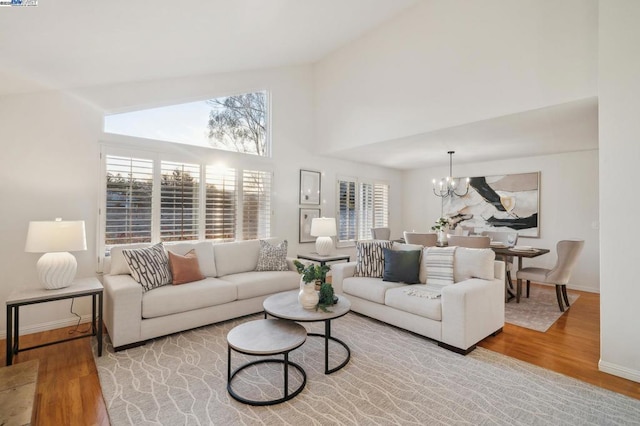 living room featuring an inviting chandelier, high vaulted ceiling, and light hardwood / wood-style floors