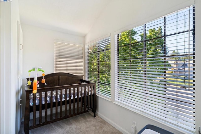 carpeted bedroom featuring a crib and lofted ceiling