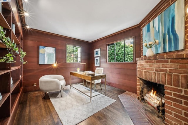 office space featuring hardwood / wood-style flooring, wooden walls, crown molding, and a brick fireplace