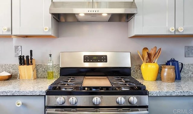 kitchen with light stone counters, stainless steel range with gas cooktop, range hood, and white cabinets