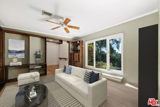 living room with light hardwood / wood-style flooring, ornamental molding, and ceiling fan