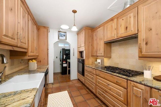 kitchen featuring sink, decorative backsplash, hanging light fixtures, light stone counters, and black appliances