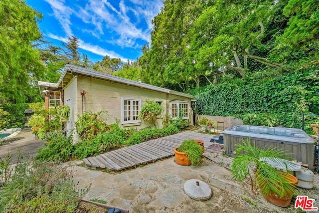 back of house featuring a hot tub, a patio, and a deck