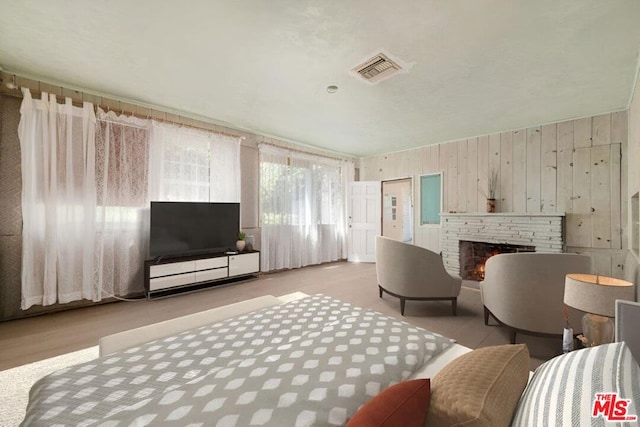 living room featuring wooden walls and a stone fireplace