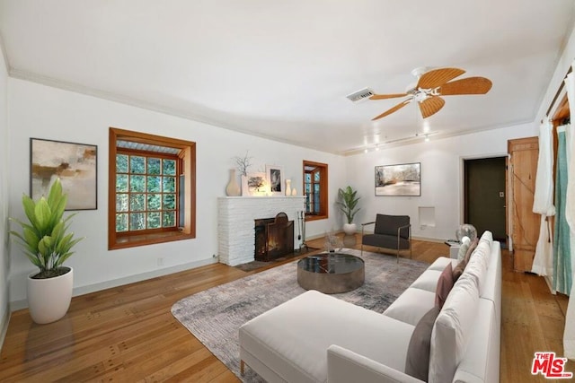 living room featuring hardwood / wood-style flooring, ceiling fan, and a fireplace