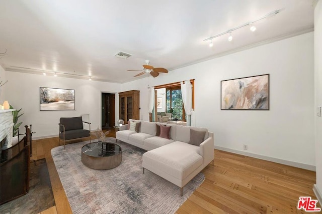 living room with rail lighting, a stone fireplace, ceiling fan, and light hardwood / wood-style flooring