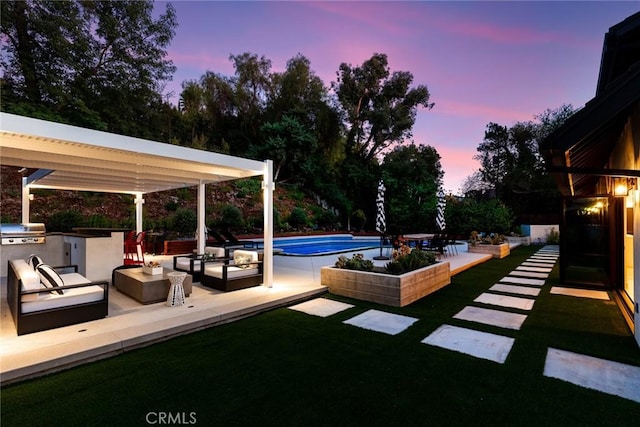 yard at dusk with an outdoor kitchen, an outdoor hangout area, a pergola, and a patio