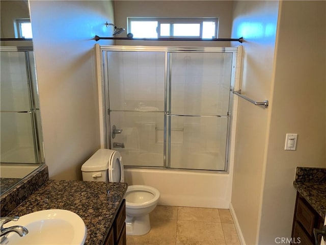 full bathroom with vanity, bath / shower combo with glass door, tile patterned floors, and toilet