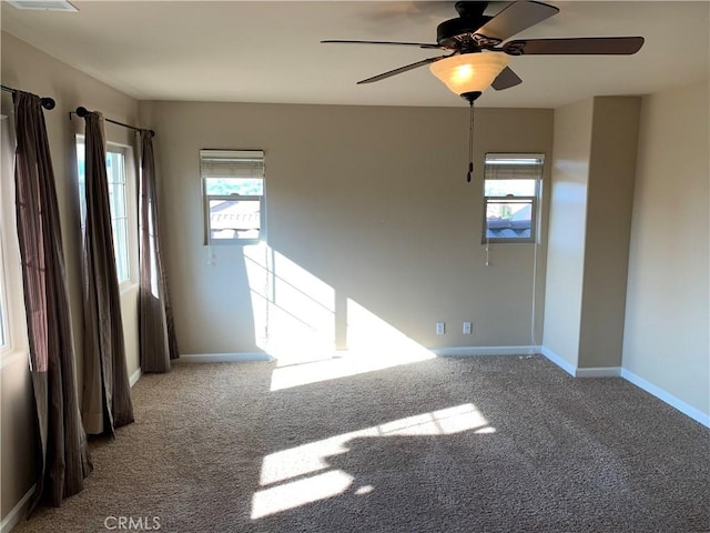 carpeted spare room featuring ceiling fan and a healthy amount of sunlight