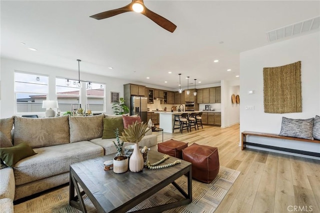 living room with ceiling fan, sink, and light hardwood / wood-style flooring