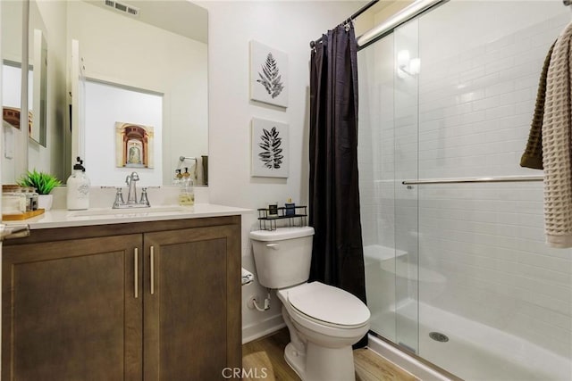 bathroom with hardwood / wood-style flooring, vanity, a shower with door, and toilet