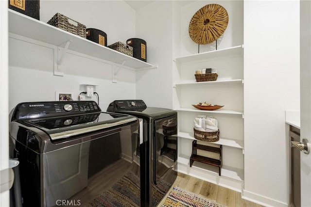 clothes washing area featuring light hardwood / wood-style flooring and washer and dryer