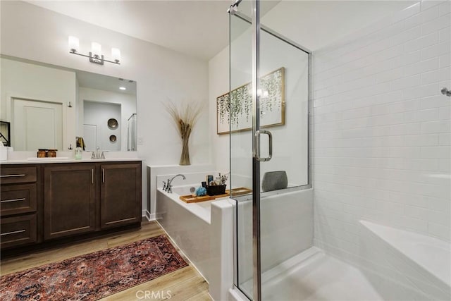 bathroom with hardwood / wood-style flooring, vanity, and shower with separate bathtub