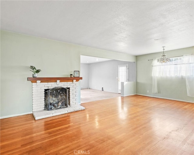 unfurnished living room featuring a brick fireplace, light hardwood / wood-style floors, and a textured ceiling