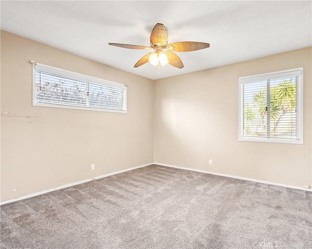 carpeted spare room featuring a healthy amount of sunlight and ceiling fan