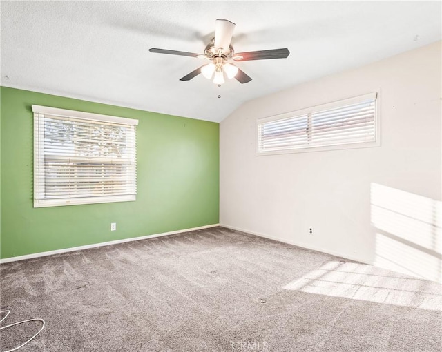 empty room featuring a textured ceiling, carpet floors, ceiling fan, and vaulted ceiling