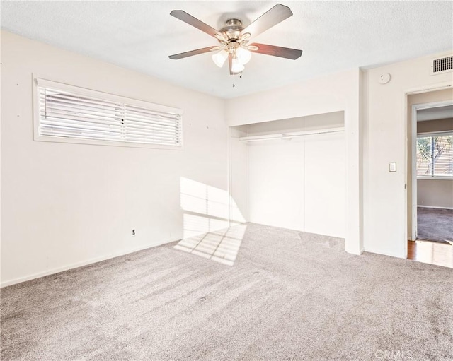 carpeted spare room featuring ceiling fan and a textured ceiling