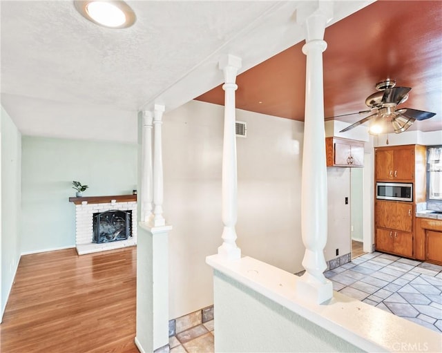 bathroom with ceiling fan, hardwood / wood-style floors, decorative columns, a fireplace, and a textured ceiling