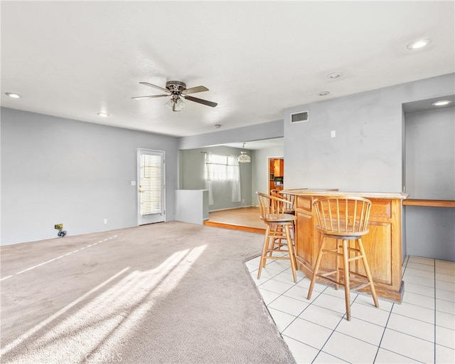 kitchen featuring a breakfast bar area, light colored carpet, and ceiling fan