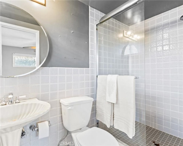 bathroom featuring walk in shower, sink, tile walls, and toilet